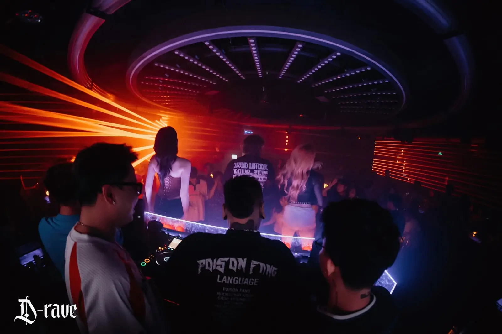 Laser cam quét ngang phòng phía sau bốt DJ, vòng đèn trần sáng tím tại D-Rave Club SGN