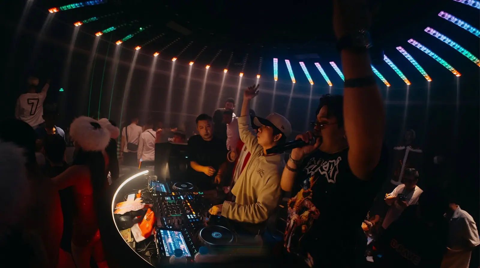 MC cầm micro cạnh DJ ở bốt tròn viền đèn, đèn LED xếp hình nan quạt trên trần Drave Club