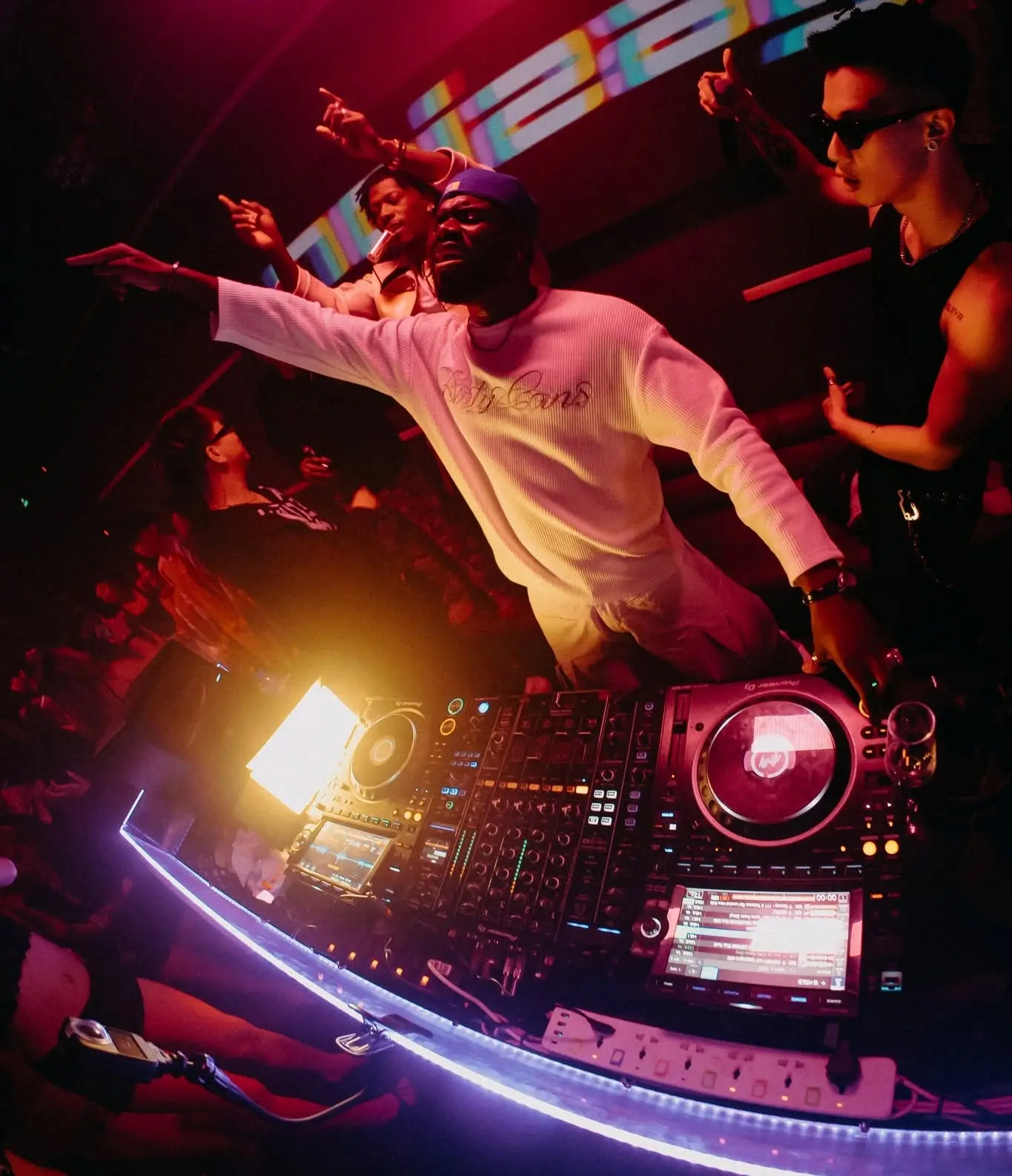 Nghệ sĩ khách mời dang tay sau bàn mix có viền đèn cong tại D-Rave Club SGN
